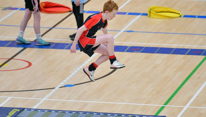 a boy dressed in PE kit jumping