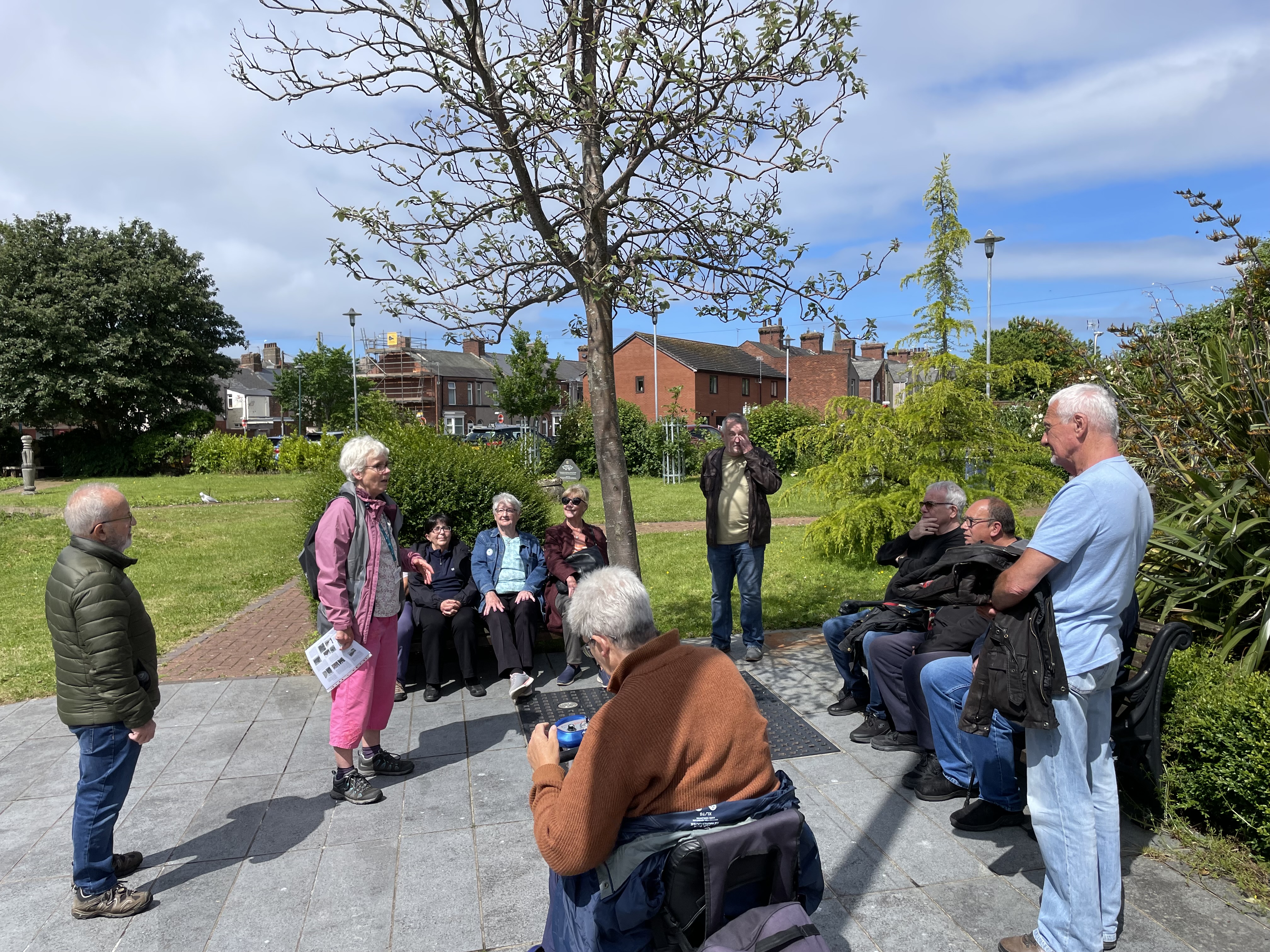 A group of mixed adults standing in a park on a sunny day