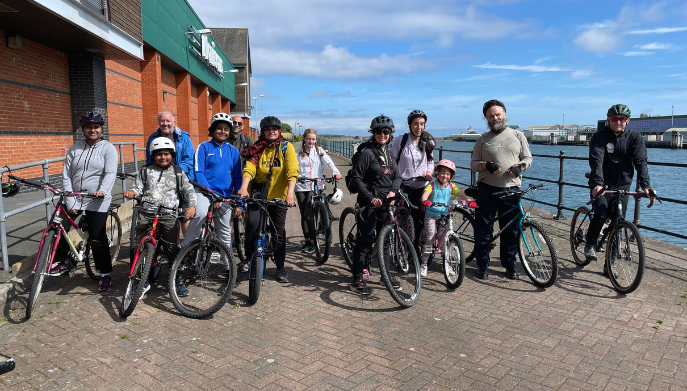 A group of mixed children and adults stood with cycles on a cycle path