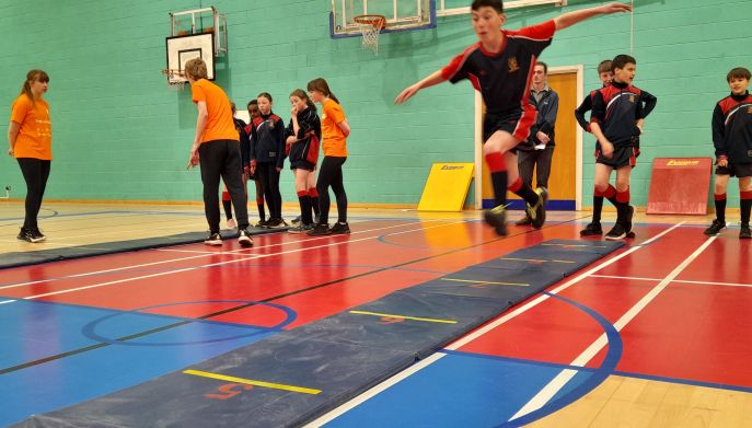 a young male dressed in sports clothing taking part in a hop skip jump activity 