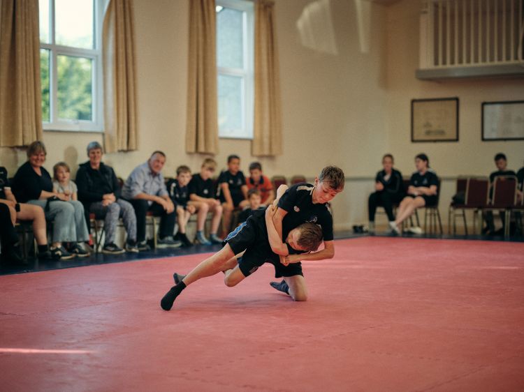 Two boys Wrestling with spectators in the background