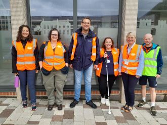 A group of walk leaders stood smiling at the camera wearing high vis jackets
