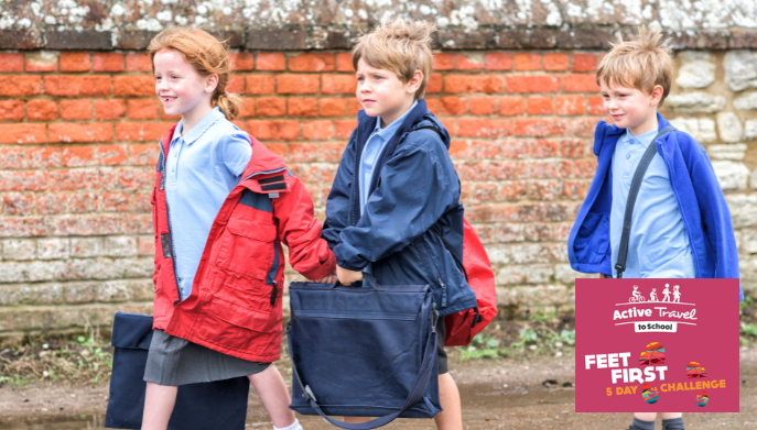 three children - a girl and two boys walking to school.  they are carrying satchels and dressed in school uniform