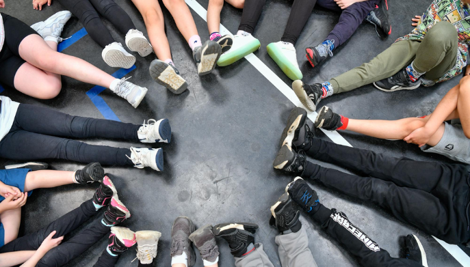 a group of children sat down in a circle - the image shows their feet and shoes
